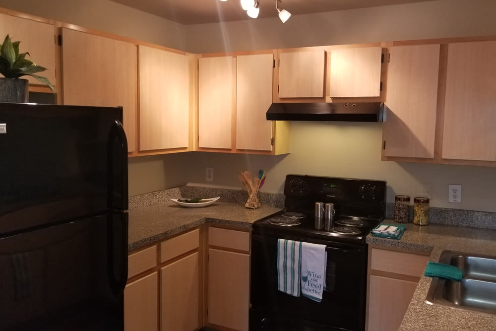 Fully-equipped kitchen with dishwasher, and wood cabinetry at The Abbey at Hightower in North Richland Hills, Texas