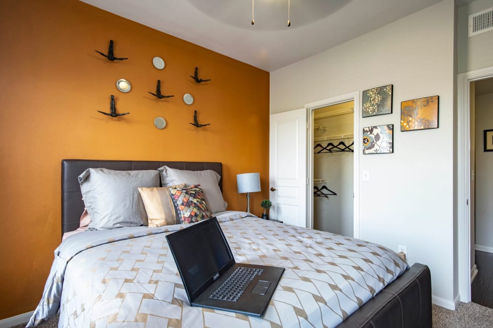 Cool orange wall behind the bed in the bedroom of a model home at The Quarry Townhomes in San Antonio, Texas