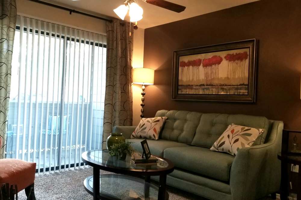 Spacious living room with couch, coffee table and access to patio through door with glass window at The Abbey at Hightower in North Richland Hills, Texas