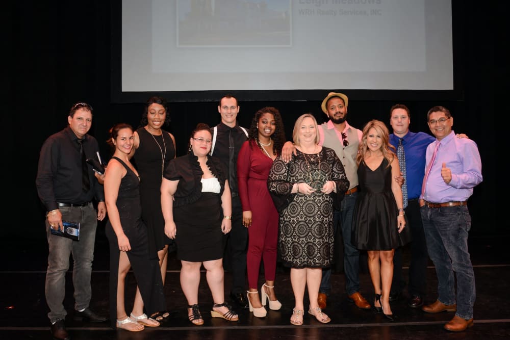 Employees from at WRH Realty Services, Inc stand on stage together