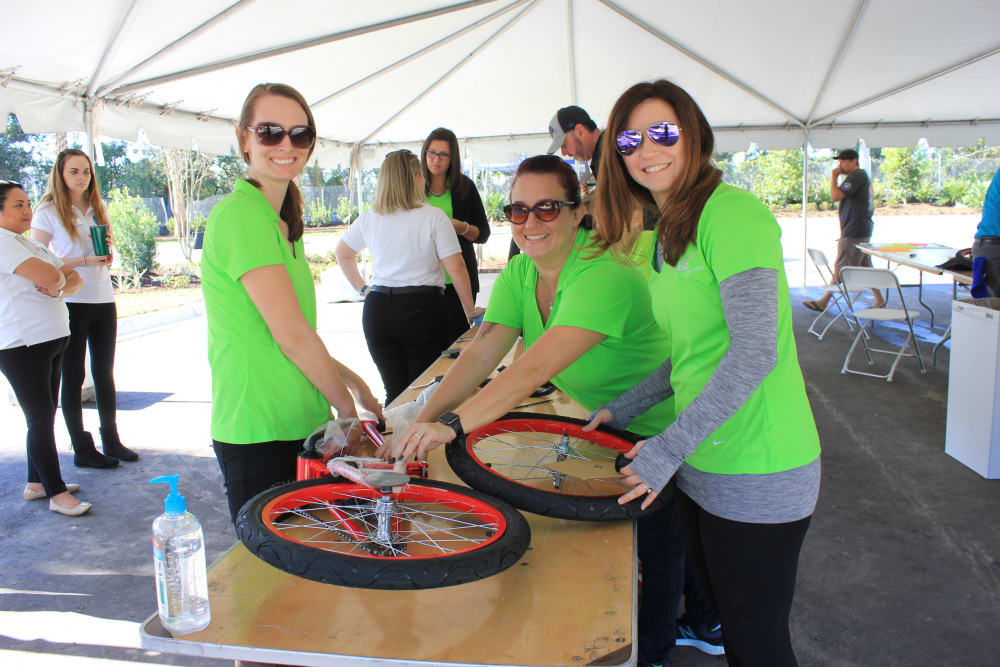 Employees pose with a new bike for kids at a local event sponsored by  WRH Realty Services, Inc 