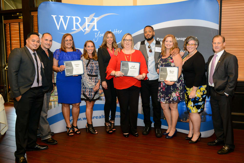 Employees at WRH Realty Services, Inc show off their awards in a group shot