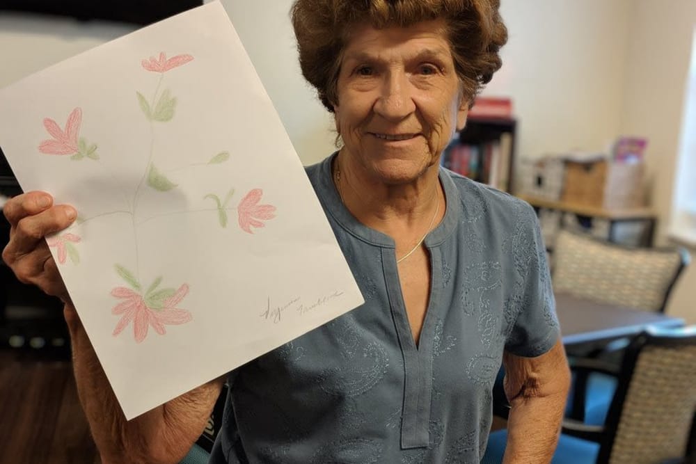 A proud resident holding her drawing at The Oaks at Woodfield in Grand Blanc, Michigan