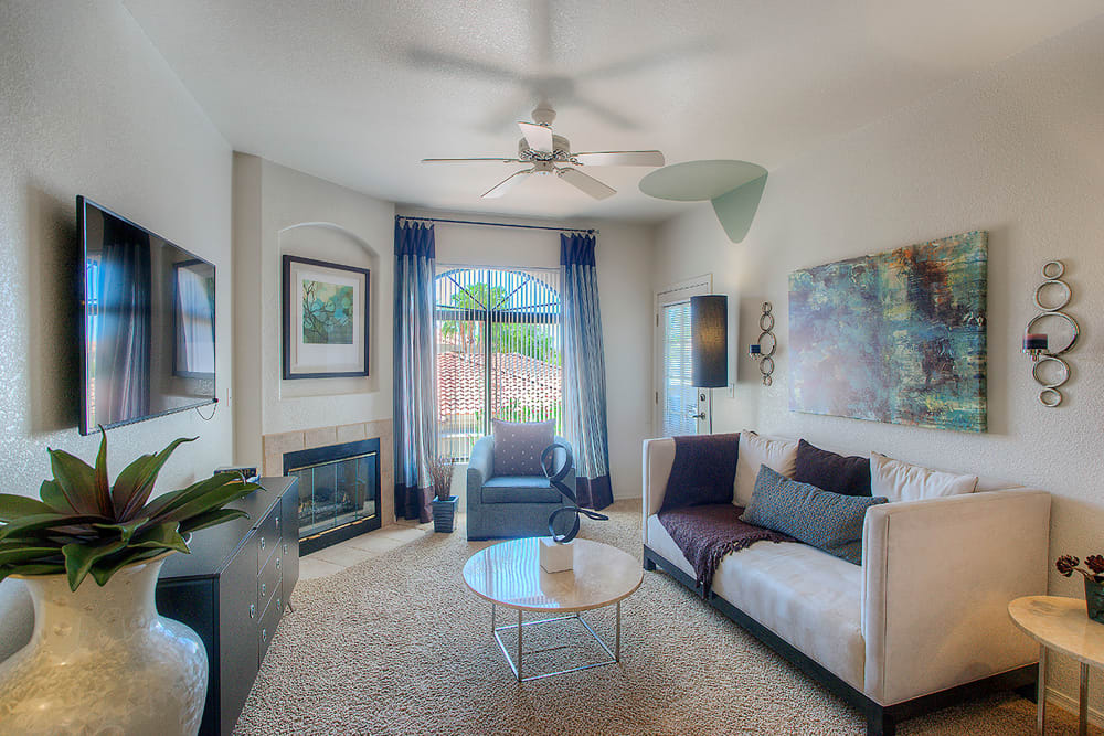 Well-decorated living room with a ceiling fan and plush carpeting in a model home at San Pedregal in Phoenix, Arizona