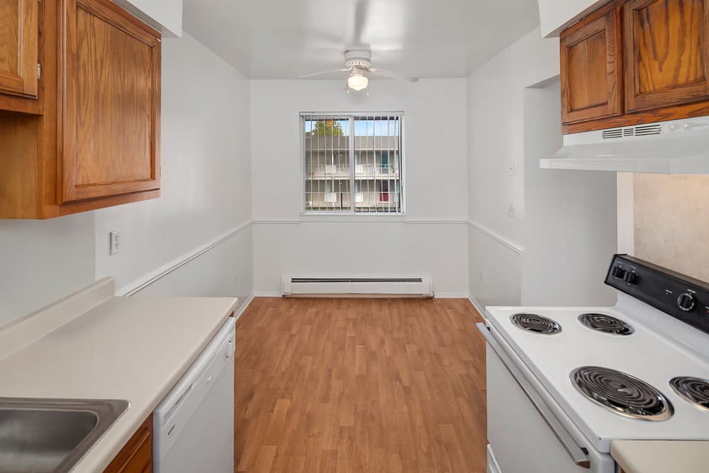 The kitchen leads to the dining room with a window at Concorde Club Apartments in Romulus, Michigan
