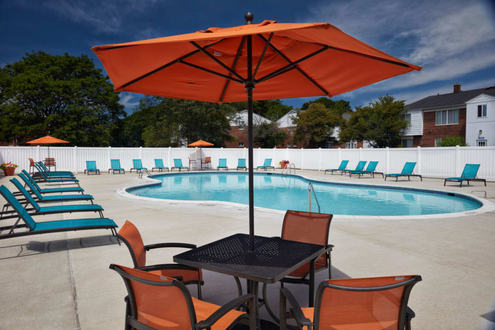 Covered patio seating next to the pool in Warren, Michigan at Harlo Apartments