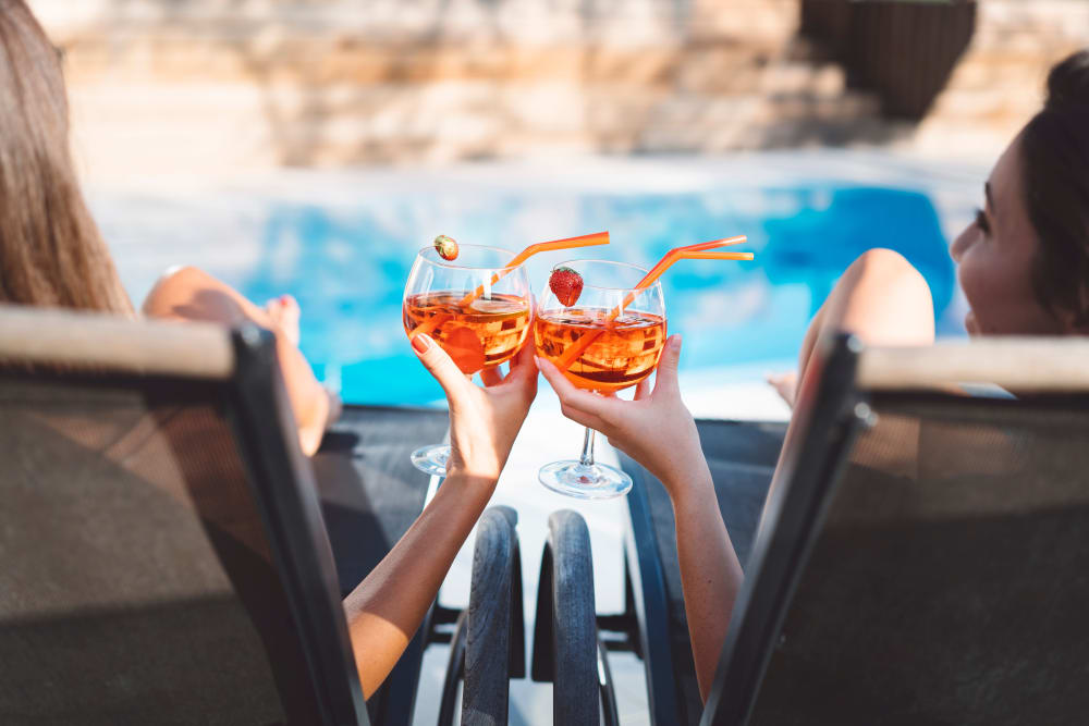 Friends enjoying cocktails next to the pool at The District at Chandler in Chandler, Arizona