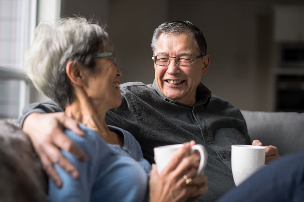 Two residents on a couch together with coffee mugs at Brightwater Senior Living of Linden Ridge in Winnipeg, Manitoba