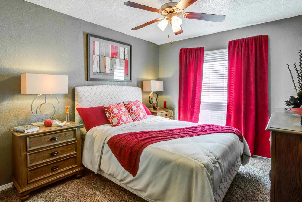 Model bedroom with ceiling fan and hardwood style flooring at Sausalito Apartments in College Station, Texas
