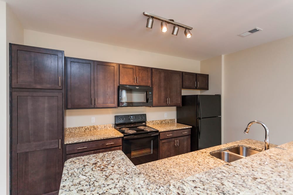 Full kitchen featuring granite countertop and dark wood cabinets at Madison Crest Apartment Homes in Madison, Tennessee