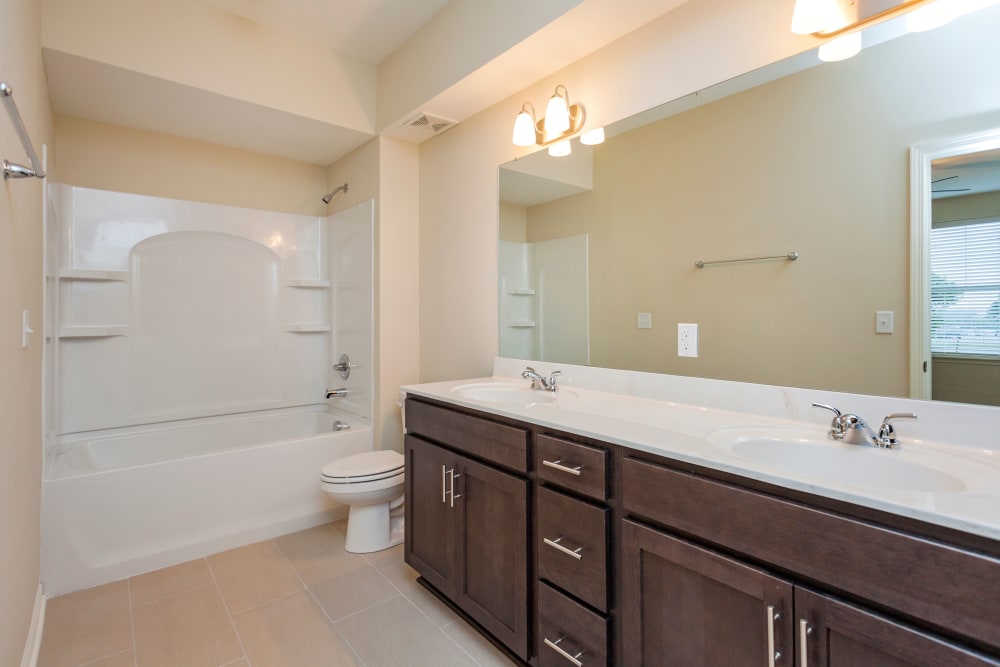 Bathroom featuring a double sink vanity with dark wood cabinets at Madison Crest Apartment Homes in Madison, Tennessee