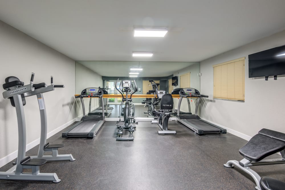 A fitness center with individual workout stations at Emerald Dunes Apartments in Miami Gardens, Florida
