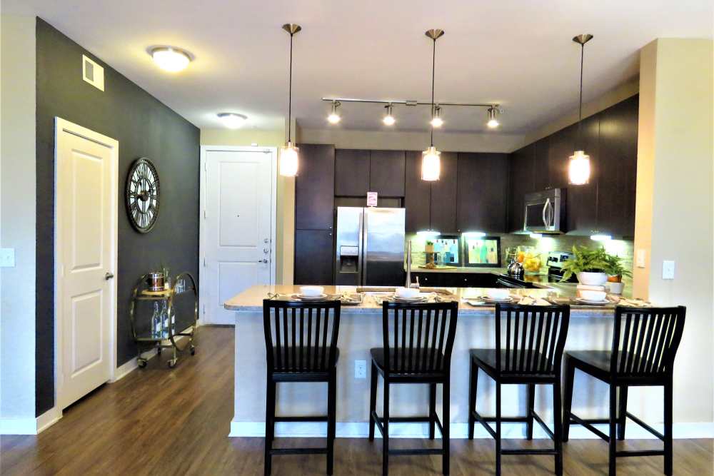 View of bright kitchen with ambient lighting at The Abbey at Spring Town Center in Spring, Texas