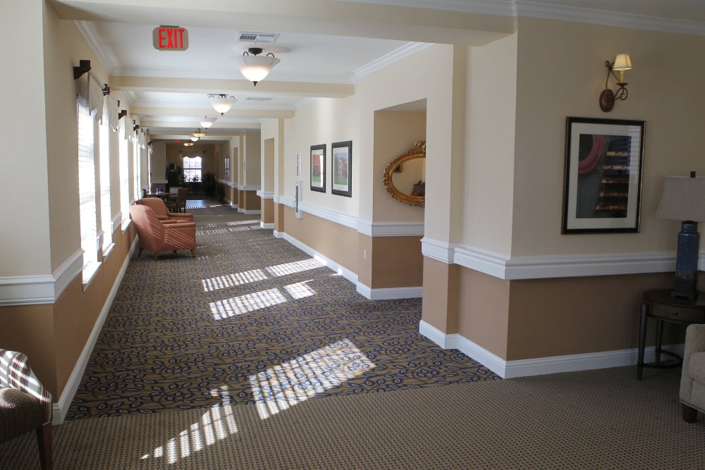 A large, carpeted hallway with a comfy chair at Isle at Raider Ranch in Lubbock, Texas