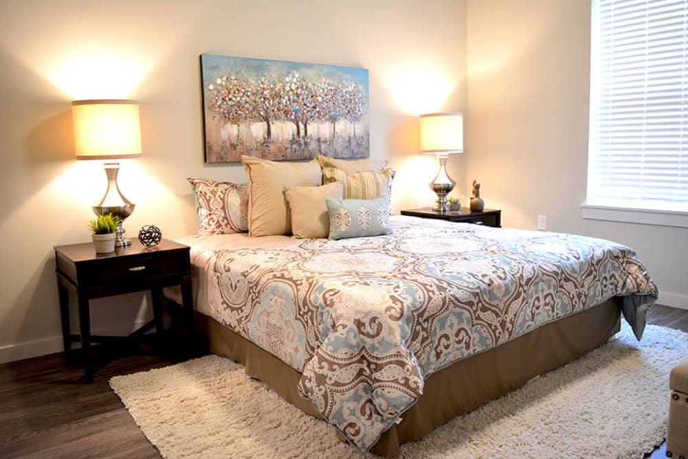 A spacious master bedroom with wood-style flooring at Pure St. Peters in Saint Peters, Missouri