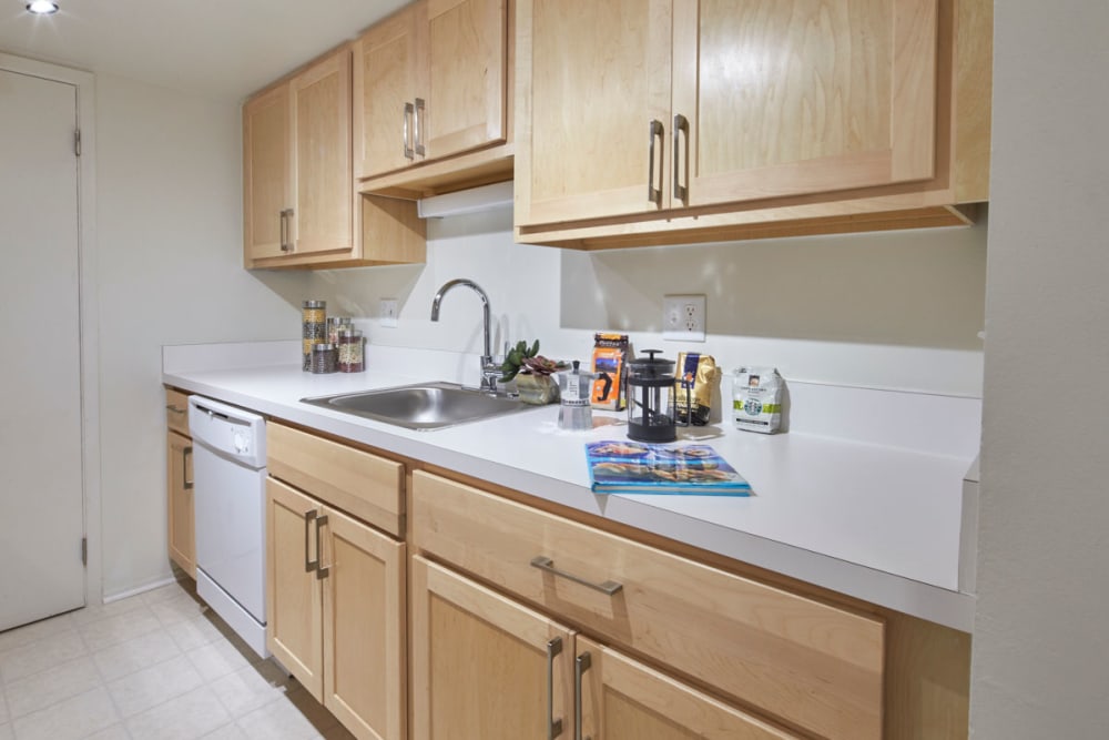 Kitchen with white appliances and stainless-steel sink at Kensington Manor Apartments in Farmington, Michigan