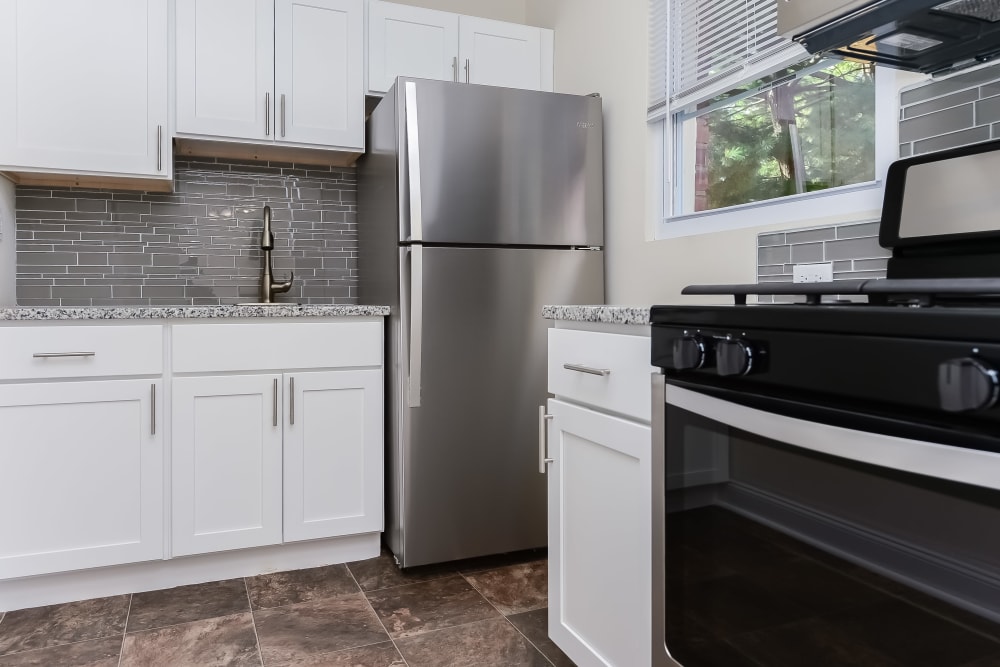 Contemporary kitchen with white cabinets and tile backsplash at Elmwood Village Apartments & Townhomes in Elmwood Park, New Jersey