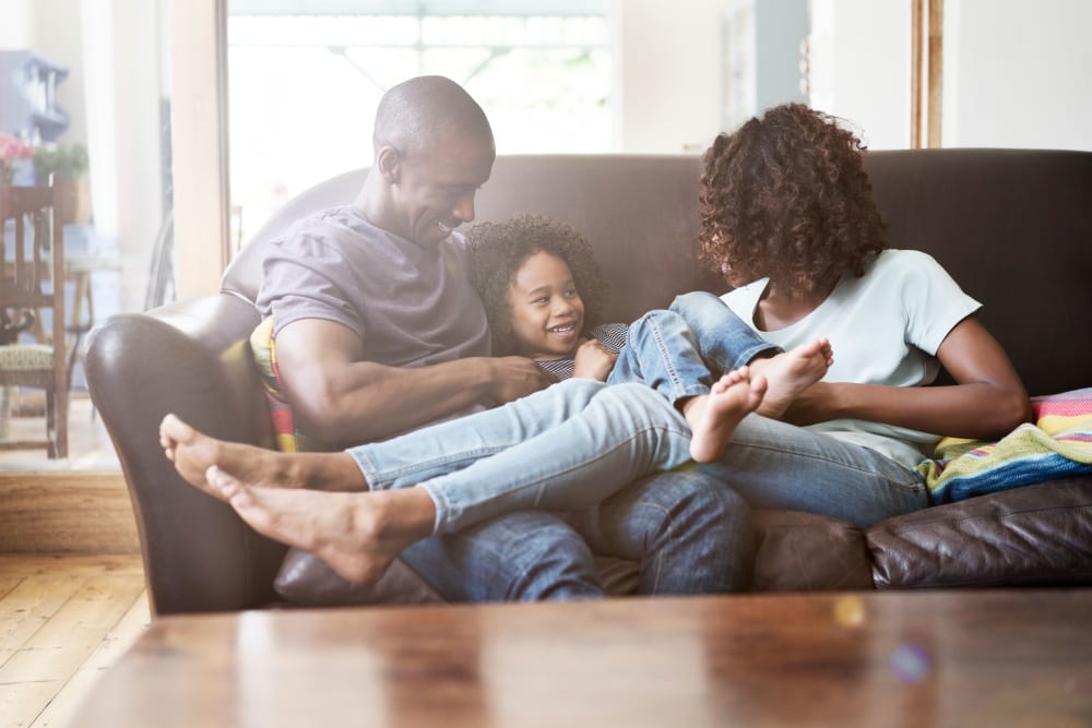 Happy family cuddling on the couch together at Oaks White Rock in Dallas, Texas