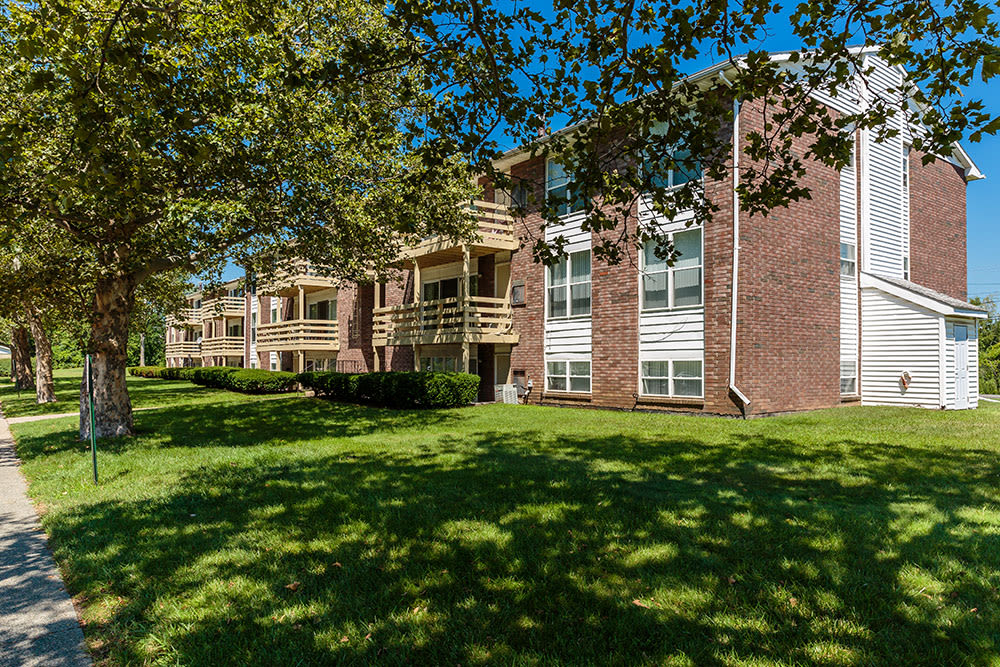 Brick building exterior and courtyard with mature trees at Hillcrest Village in Niskayuna, New York