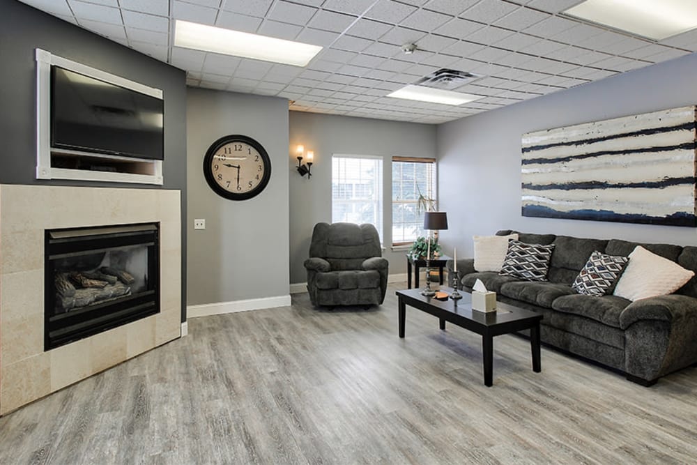 Seating area with a fireplace and large flatscreen TV in the community center at Westview Commons Apartments in Rochester, New York