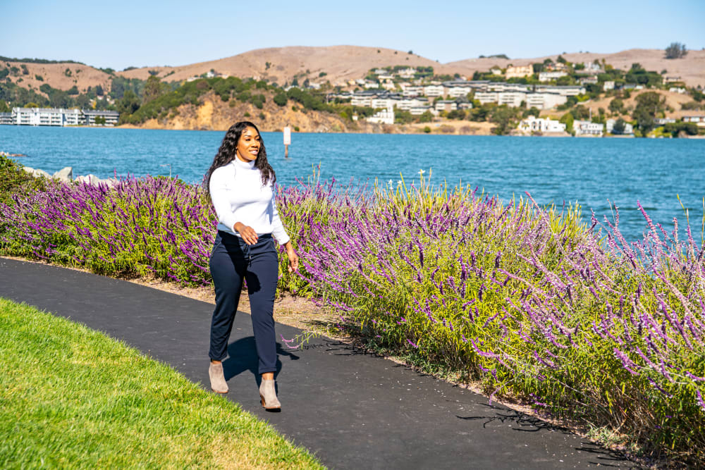 Resident walking along one of the flower-lined pathways next to the bay at Harbor Point Apartments in Mill Valley, California