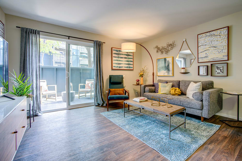 Spacious open concept living area with hardwood floors and draped sliding doors leading to the private patio of a model home at Terra Martinez in Martinez, California