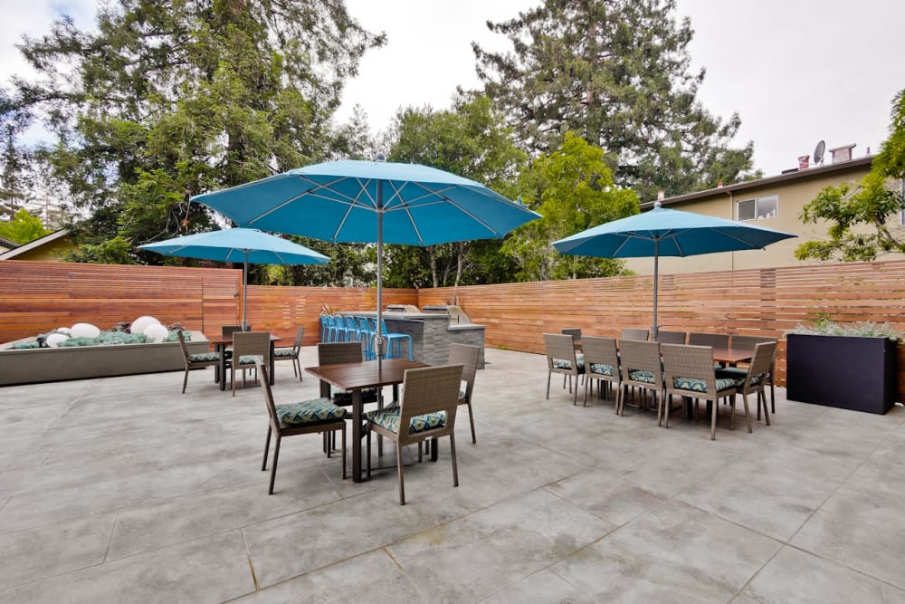 Tables with umbrellas and plenty of seating at one of the outdoor common areas at Mia in Palo Alto, California