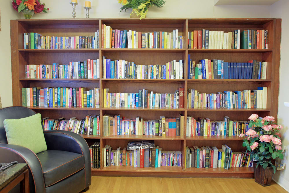 A fully stocked bookshelf with comfortable seating nearby at Bradenton Oaks in Bradenton, Florida