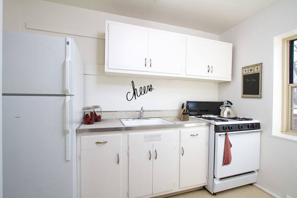 Open kitchen with white cabinetry and appliances at Brighton Gardens in Rochester, New York