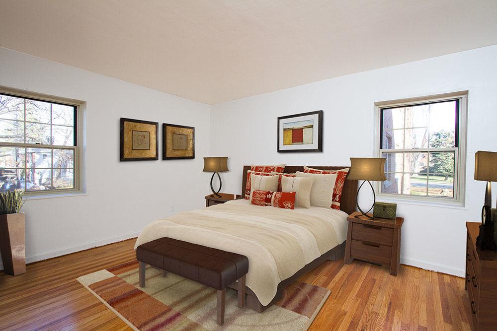 Spacious model bedroom with hardwood-style flooring at Brighton Gardens in Rochester, New York
