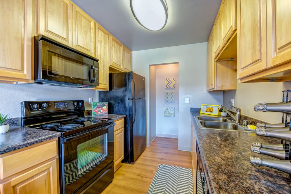 Galley-style kitchen with refrigerator, microwave, and oven/stove at Sofi Laguna Hills in Laguna Hills, California