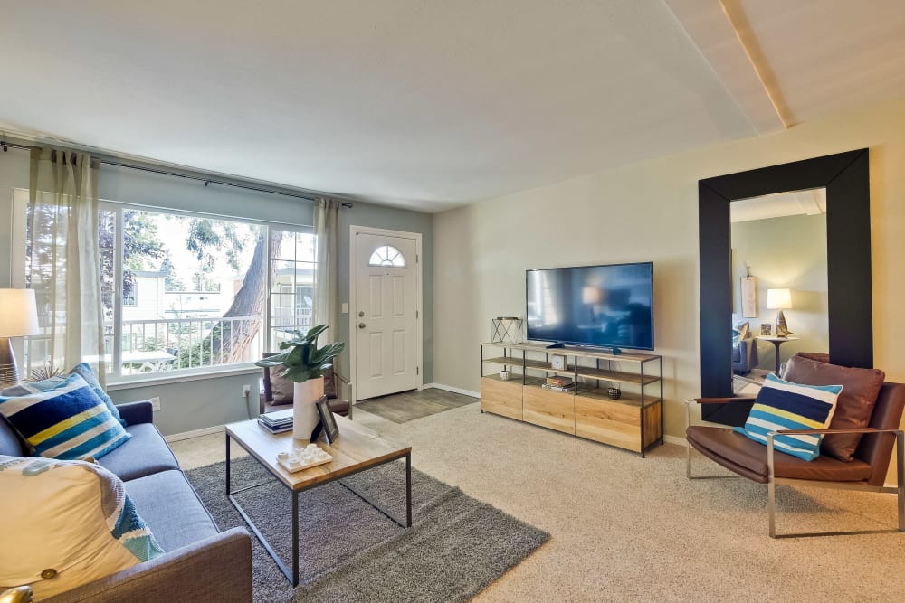 Large bay windows and plush carpeting in a model home's living space at Sofi at Los Gatos Creek in San Jose, California