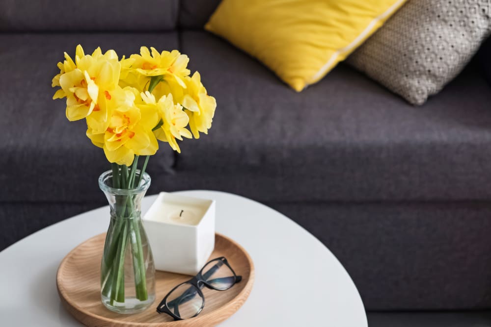 Coffee table with yellow flowers and glasses sitting on top at Hillhaven in Adelphi, Maryland