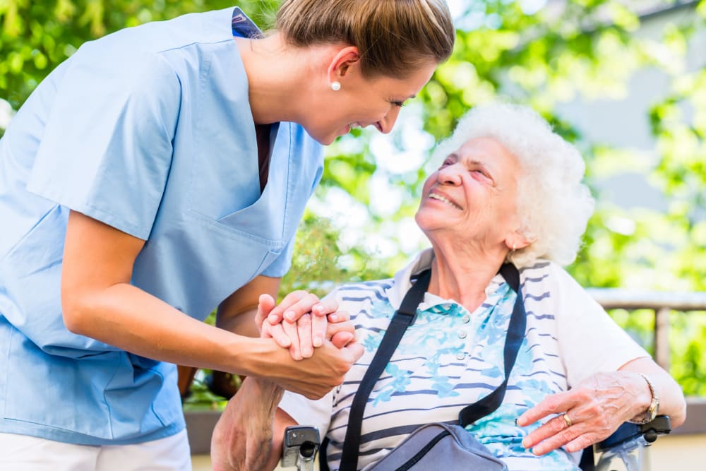 Resident holding hands and looking at a caretaker smiling at Hillhaven in Adelphi, Maryland