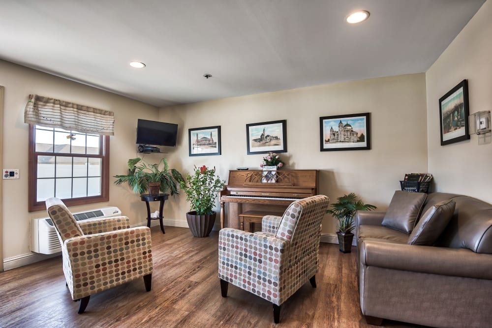 Room with a piano, chairs, and a couch at Oak Pointe of Warrenton in Warrenton, Missouri