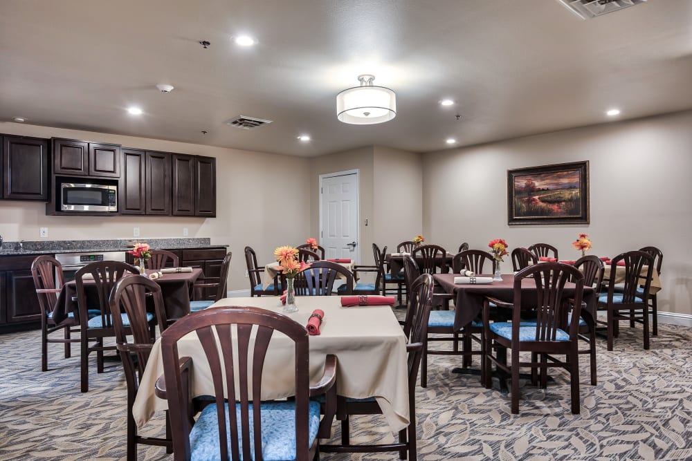 Dining hall with evenly arranged tables and chairs and a floral pattern carpet at Oak Pointe of Warrenton in Warrenton, Missouri