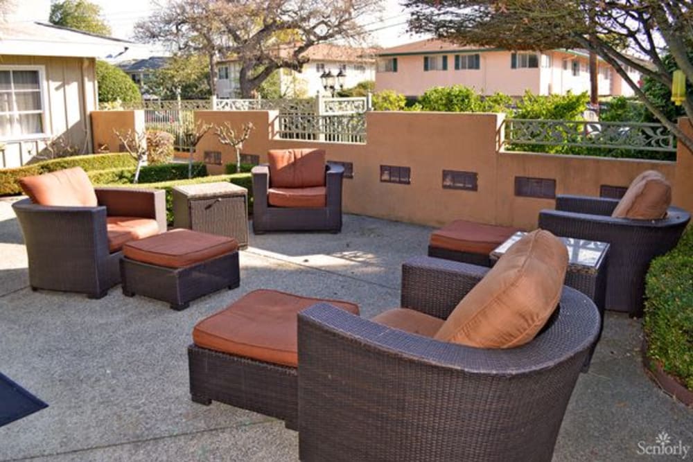 Chairs and footstools outside on the paved patio at Meadow Gardens of Menlo Park in Menlo Park, California