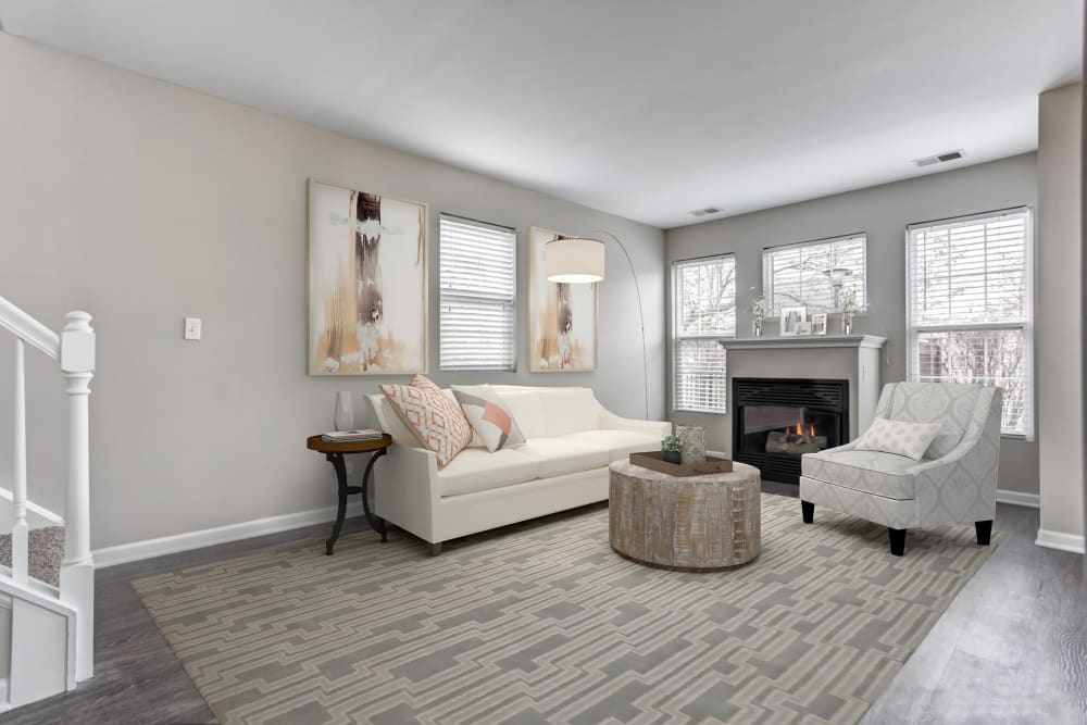 An apartment living room with white furniture, fireplace, and area carpet at Lakeview Townhomes at Fox Valley in Aurora, Illinois