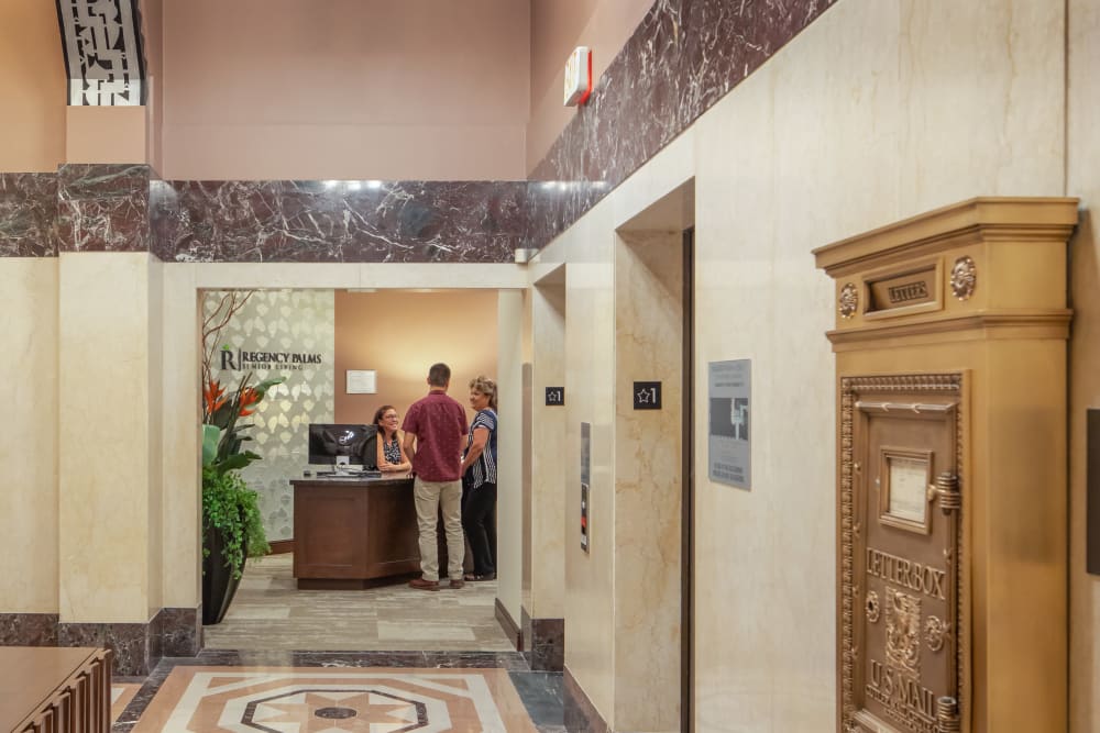 People talking to reception in the lobby at Regency Palms Long Beach in Long Beach, California