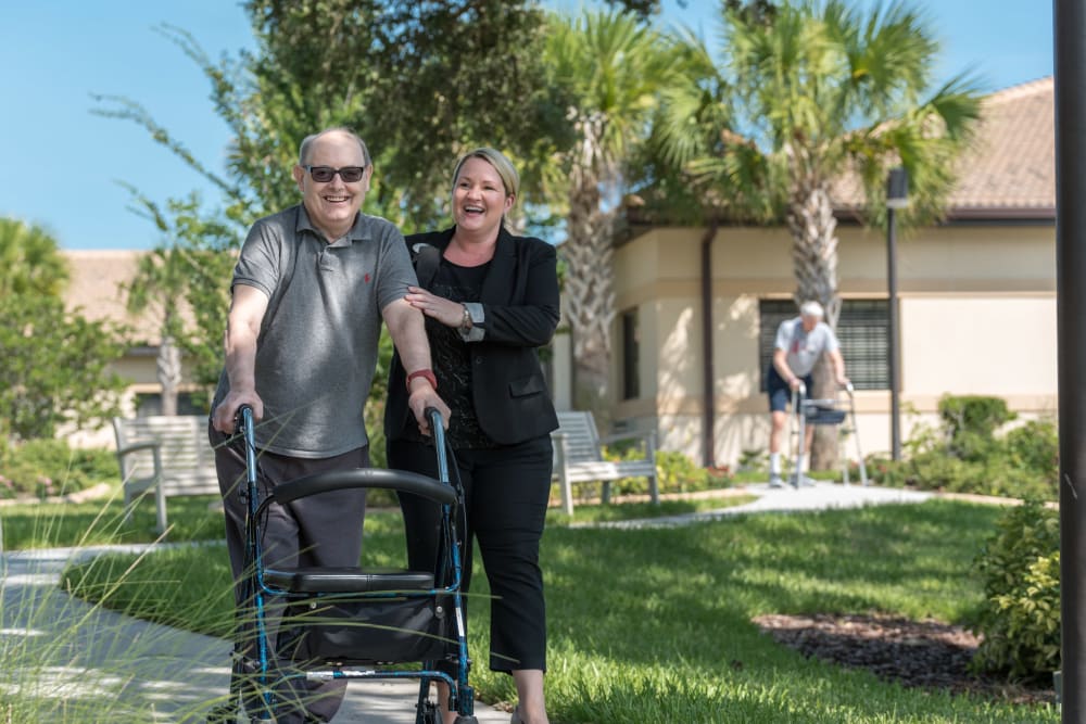 Resident out for a walk with a staff member at Inspired Living Hidden Lakes in Bradenton, Florida. 