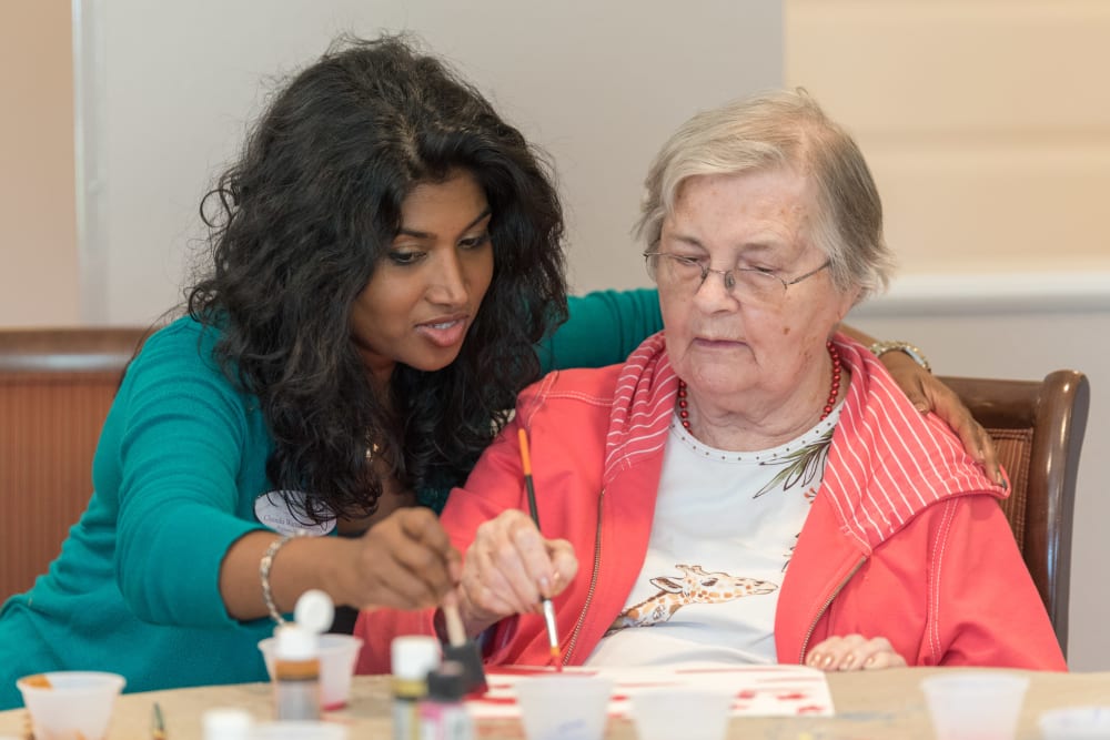 A staff member helping a resident with an art project at Inspired Living Kenner in Kenner, Louisiana. 