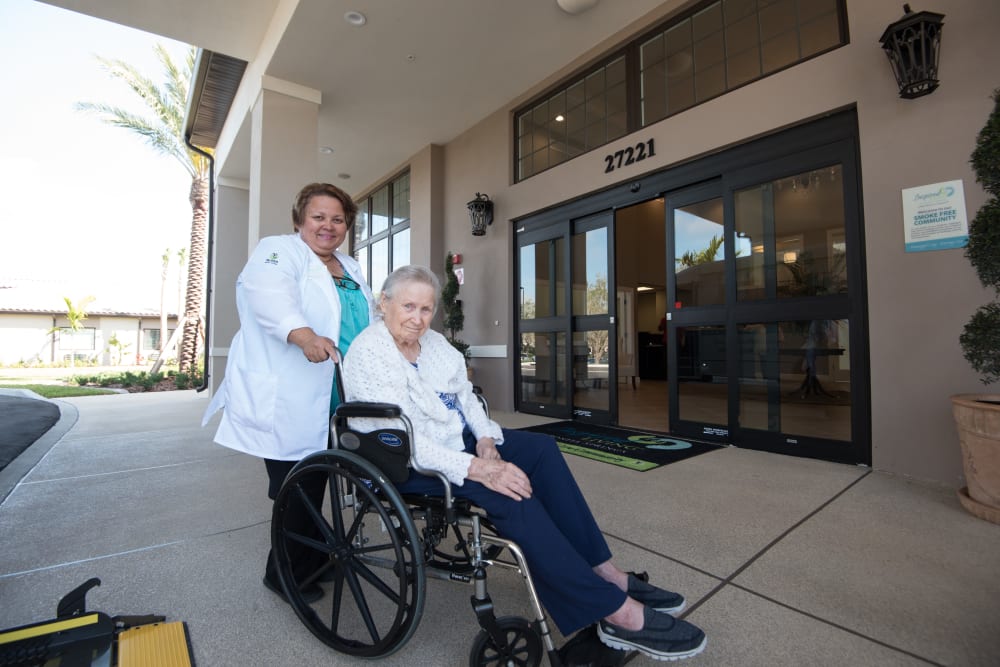 A staff member helping a resident in a wheelchair to their room at Inspired Living Kenner in Kenner, Louisiana. 