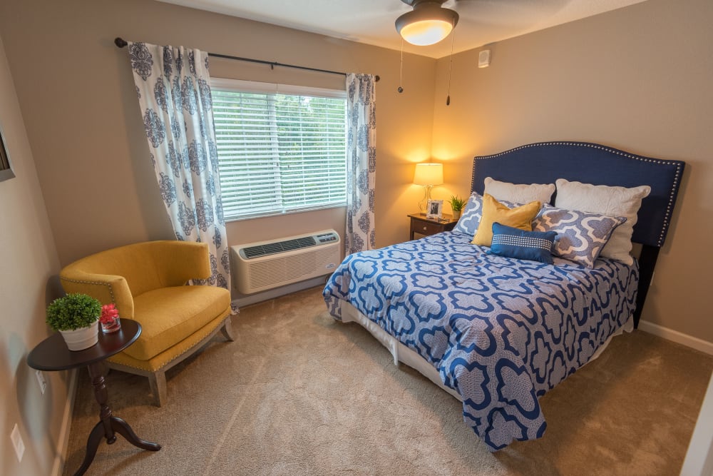 Model resident bedroom with a large window at Inspired Living in Royal Palm Beach, Florida.