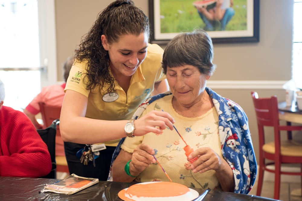 A resident painting with help from a staff member at Inspired Living Lewisville in Lewisville, Texas. 