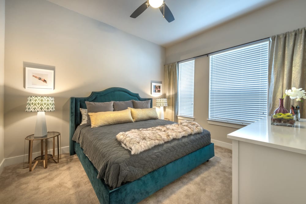 Plush carpeting and a ceiling fan in a model home's bedroom at Olympus at Ross in Dallas, Texas