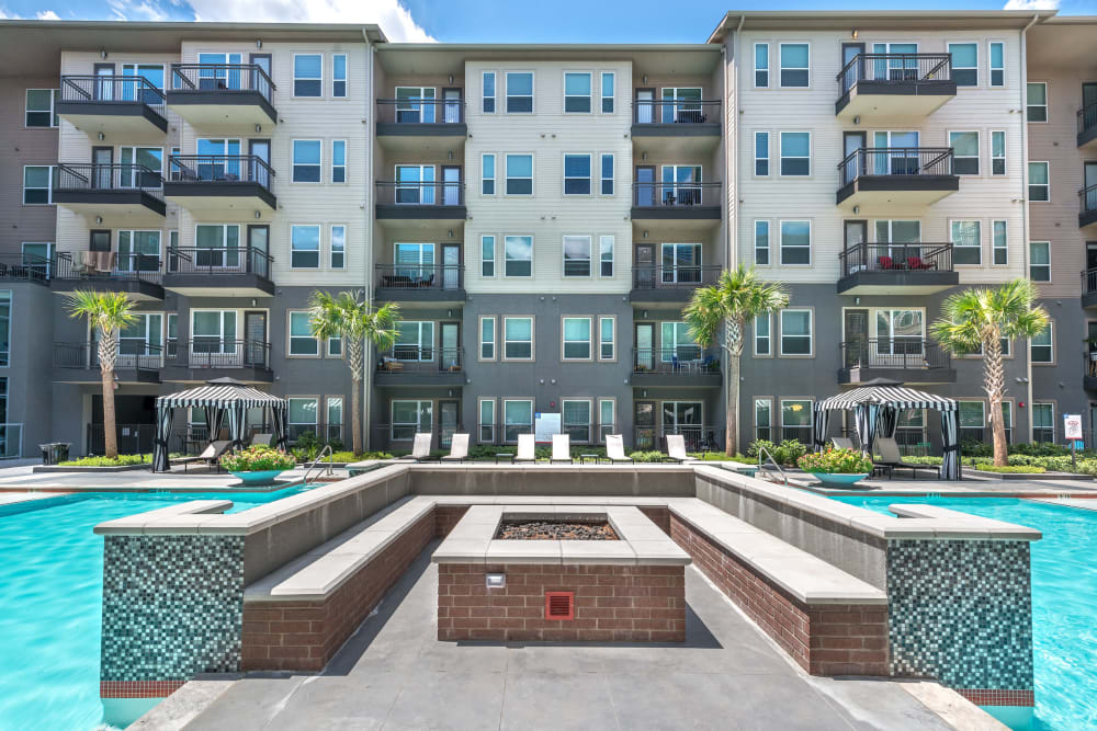Fire pit area surrounded by the swimming pool at Olympus at Ross in Dallas, Texas