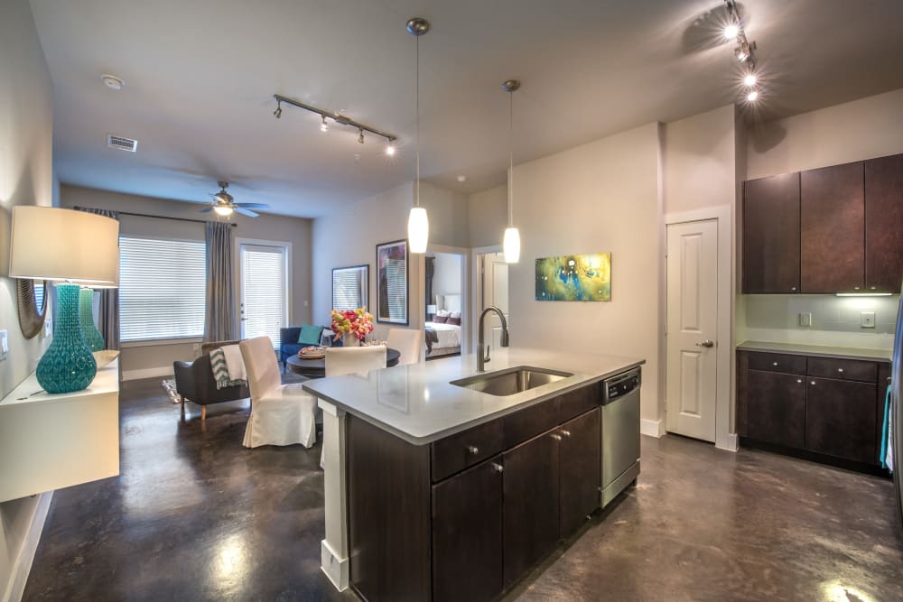 Open-concept kitchen and living area with glazed concrete flooring in a model home at Olympus at Ross in Dallas, Texas