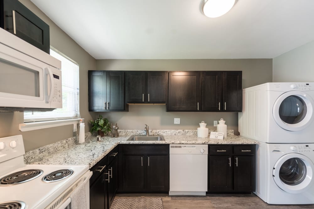 An upgraded apartment kitchen with a stacked washer and dryer at The Springs in Parkville, Maryland