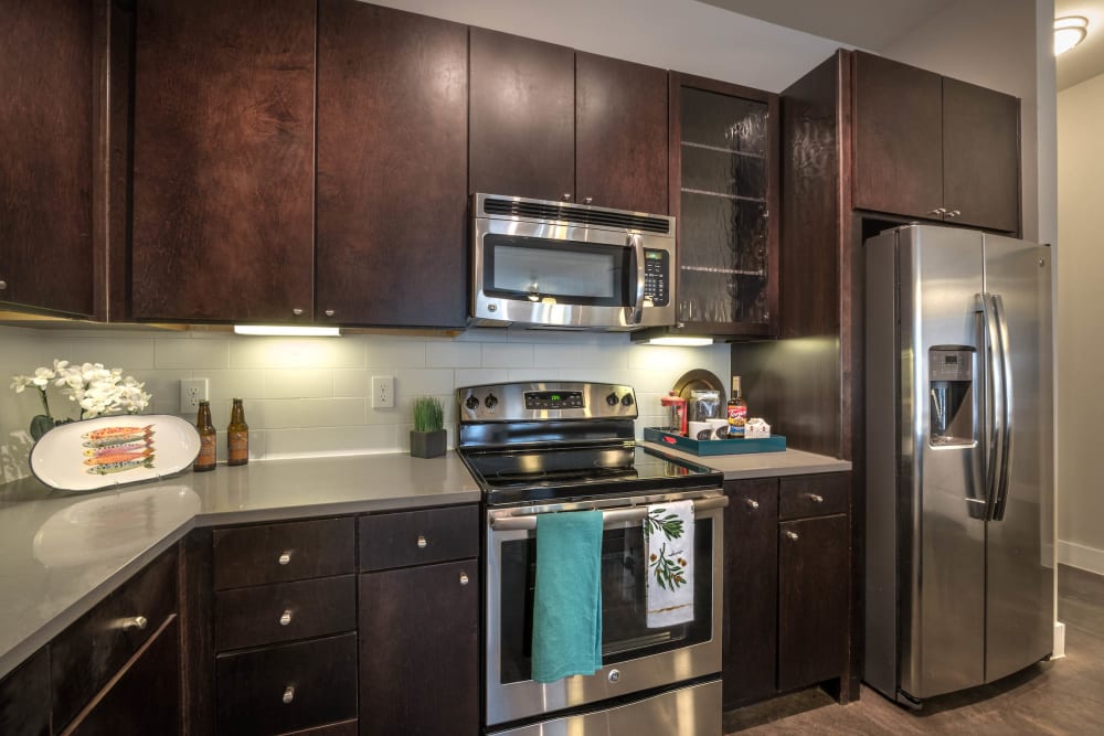 Beautiful dark wood cabinetry and stainless-steel appliances in a model home's kitchen at Olympus at Ross in Dallas, Texas