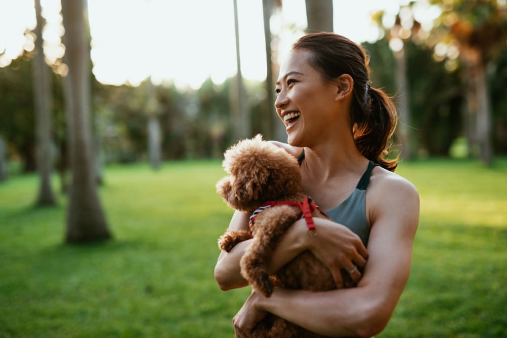 Resident holding her dog at a park in Conroe, Texas near Enclave at Woodland Lakes